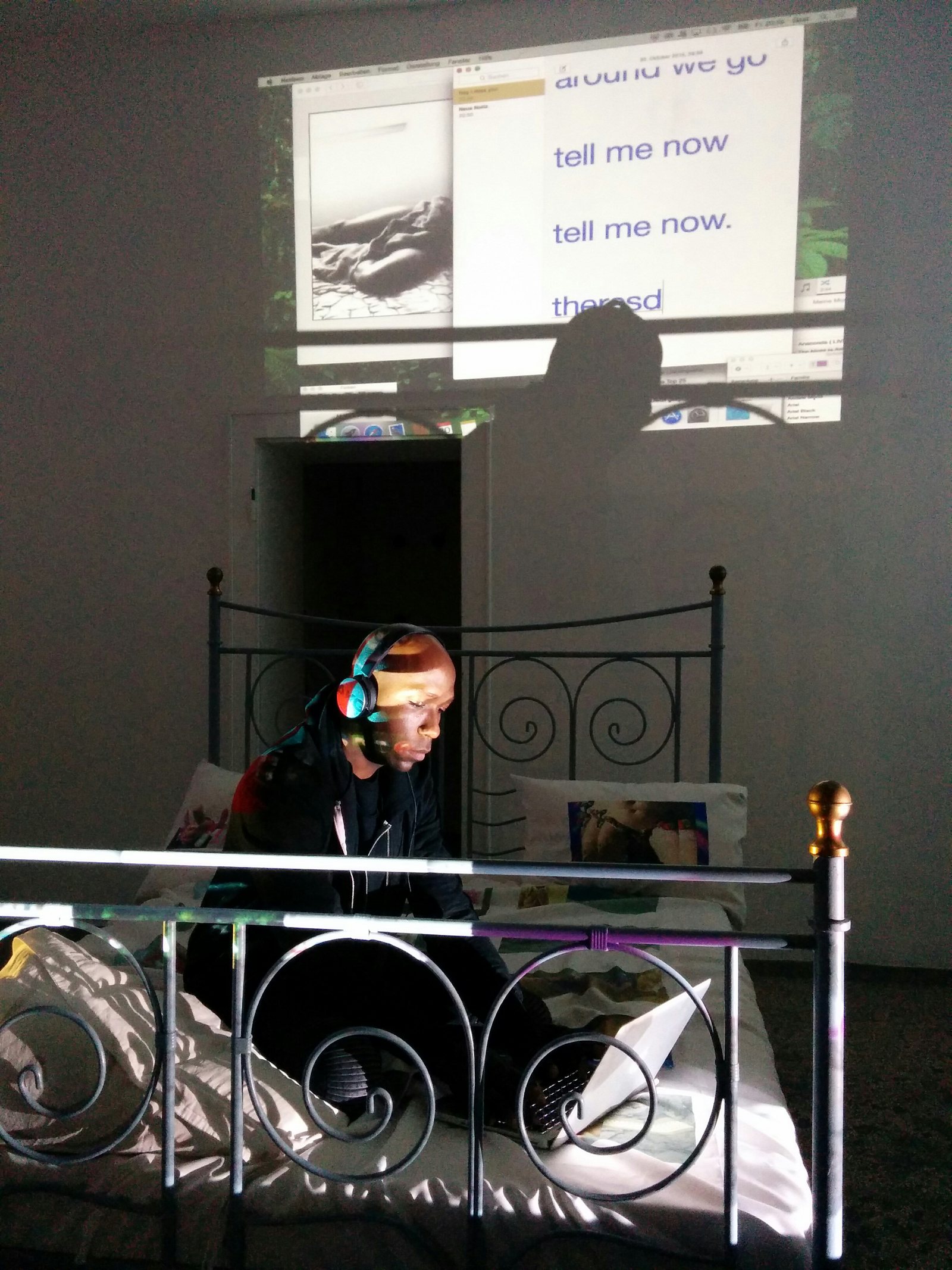 Exploit & Disappear — performer with headphones on a bed, projections above