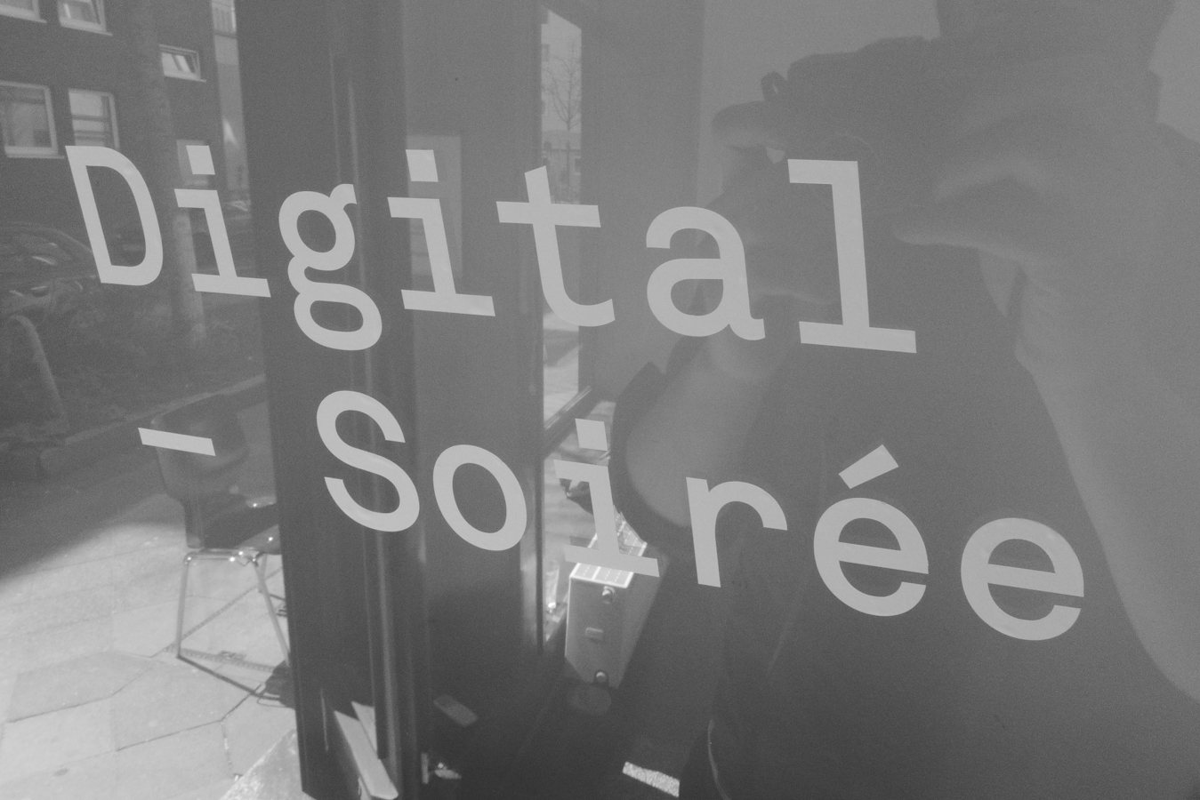 Digital-Soirée 1 — the shop window lettered 'Digital Soirée', the street reflected