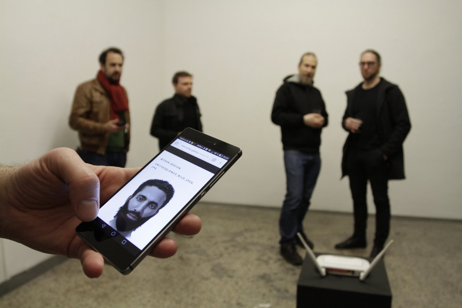 Router Gallery — a phone showing now.router.gallery, the router on its pedestal behind