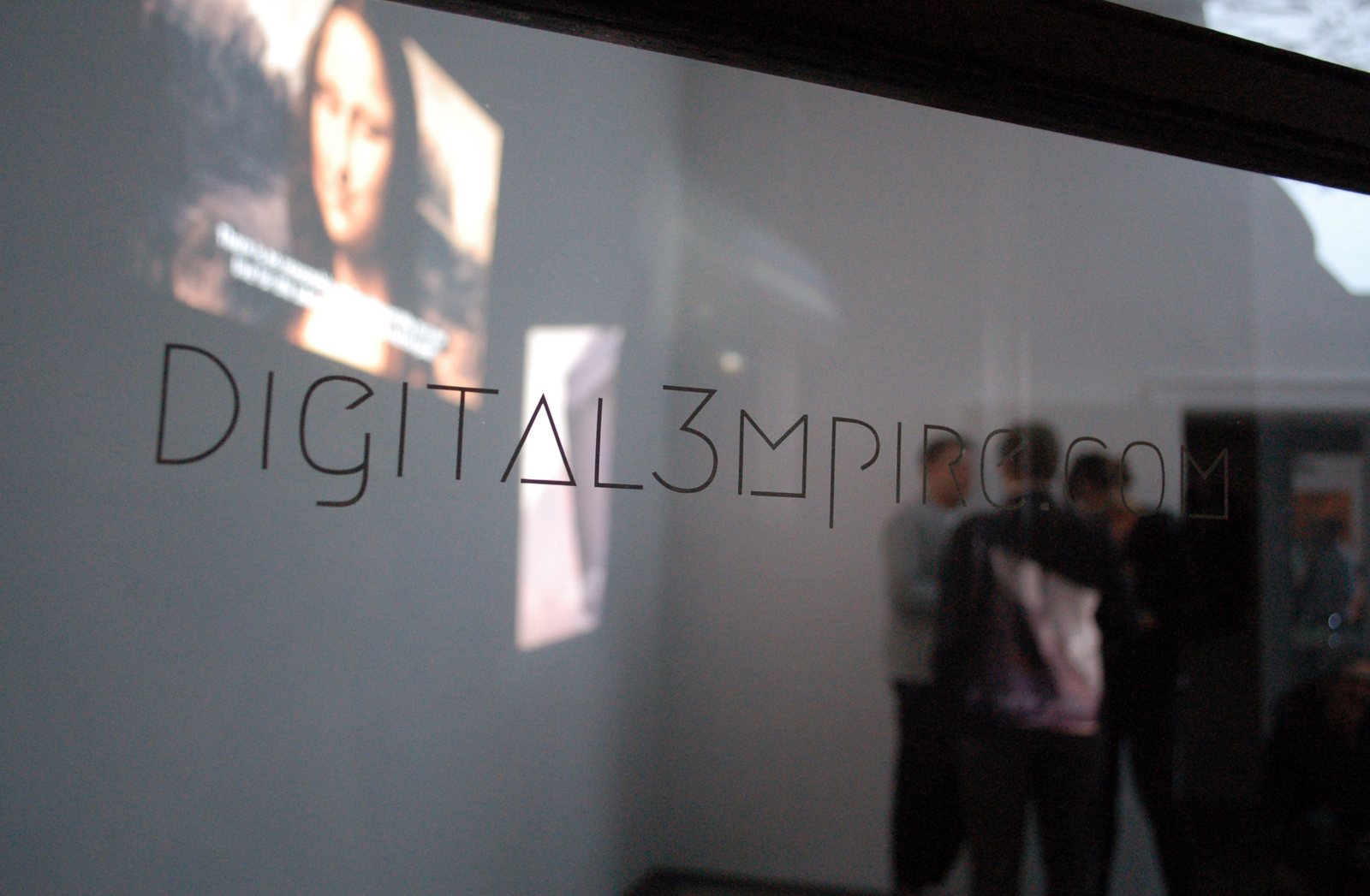 digital3mpire.com — the logo on the gallery window, visitors reflected in the glass